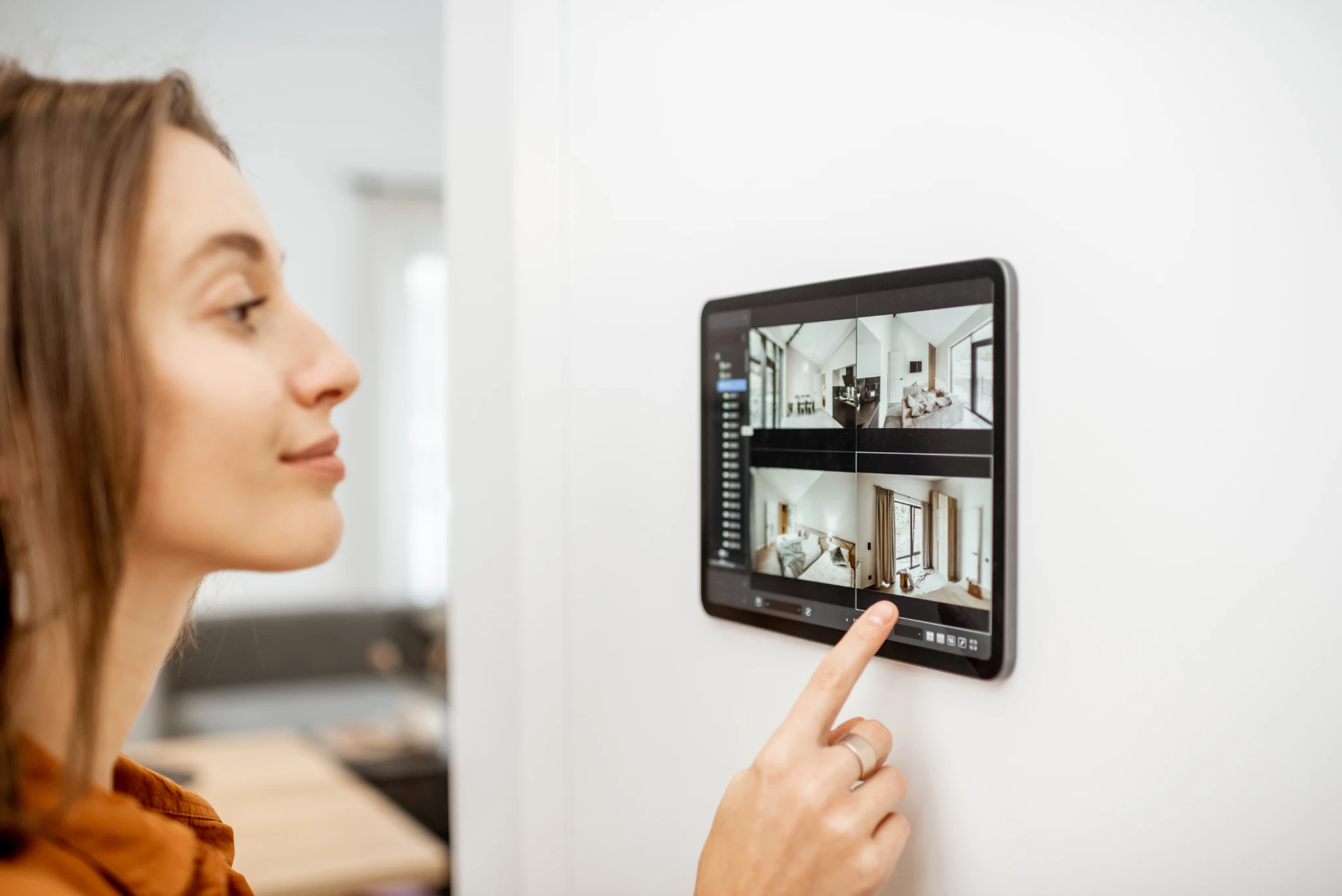 Woman interacting with a smart home security system on a wall-mounted tablet.