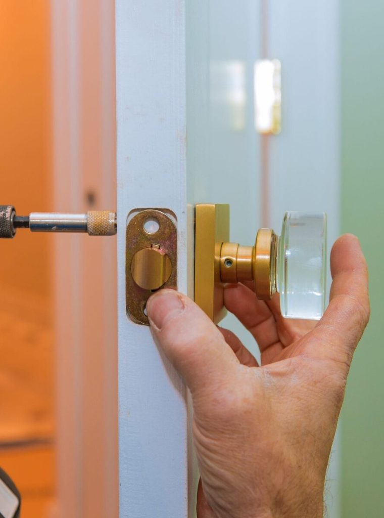 Close-up of hands installing a new door handle with a power drill.