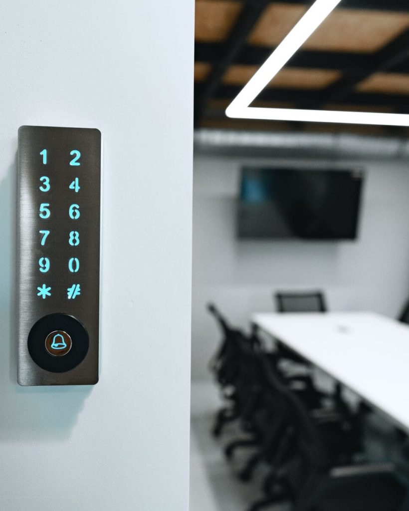 Keypad with glowing numbers on a white wall, blurred conference room in background