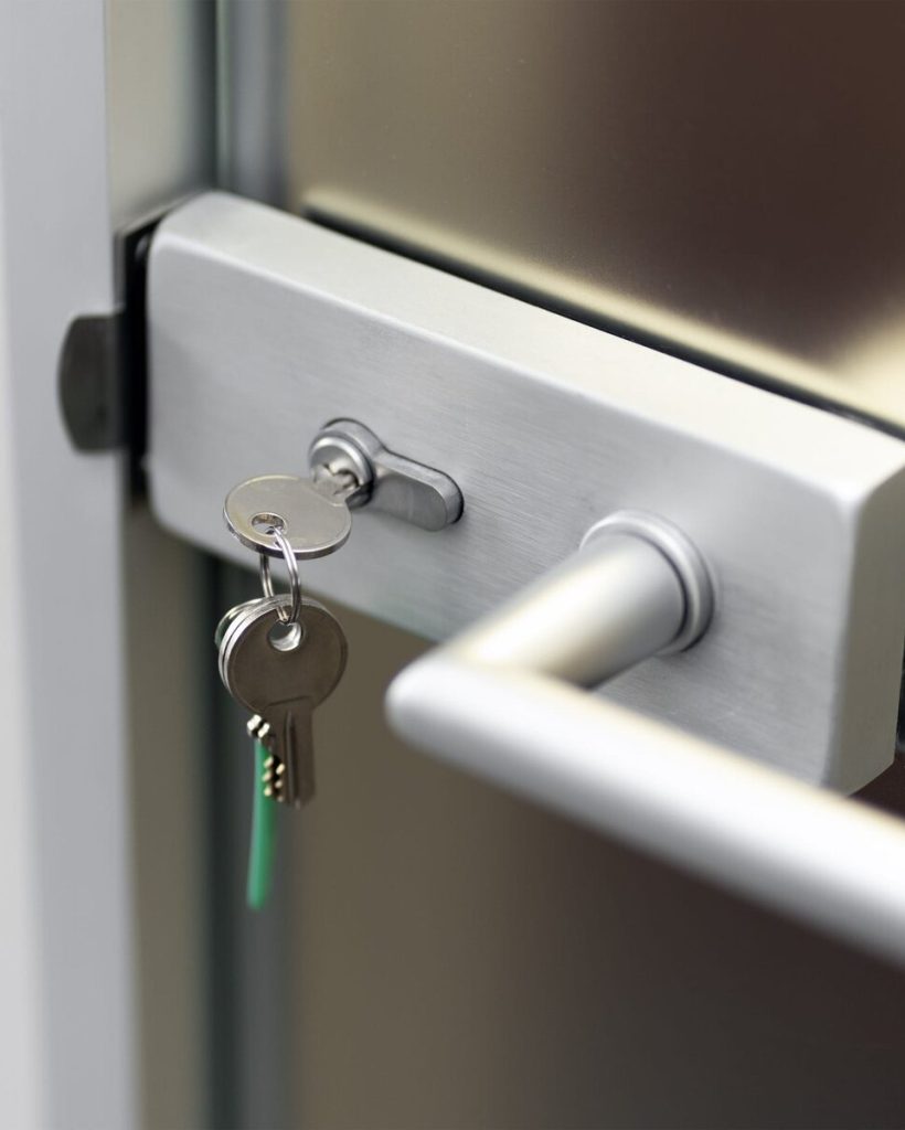 Close-up of a silver door handle with keys in the lock.